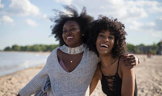 two women hugging and smiling on the beach